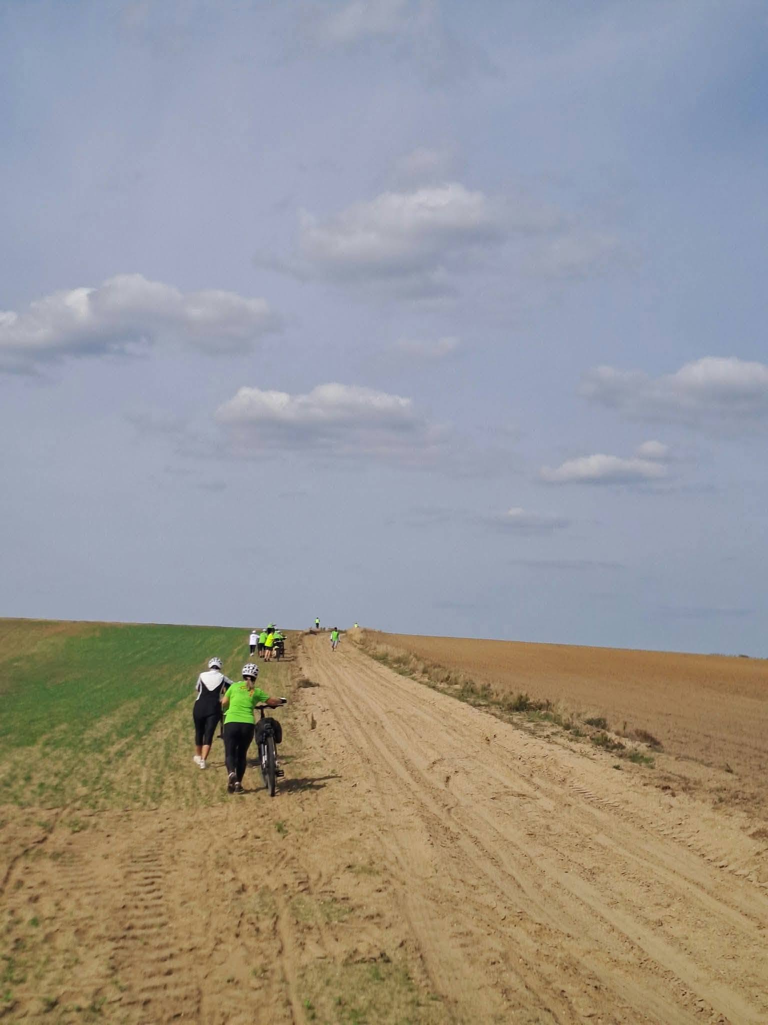 Kerékpáros túra résztvevői földúton, mezőgazdasági területen